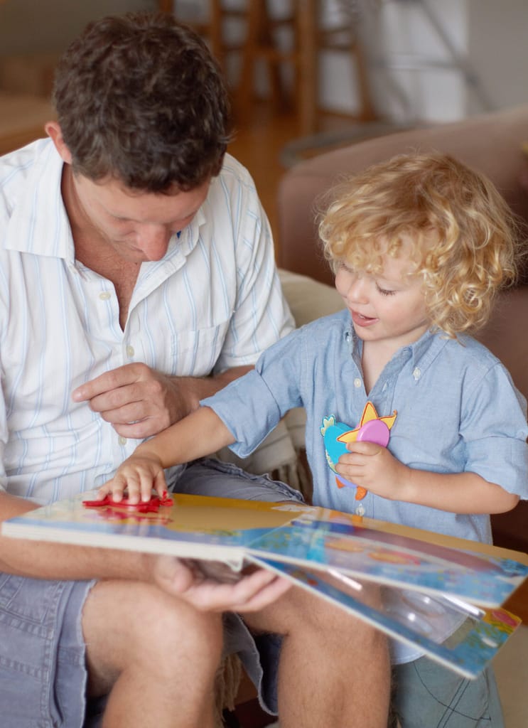 Man with boy child, reading book for education and development, spending quality time together at home. Family, teaching and learning with father and kid bonding, picture story with toys for growth